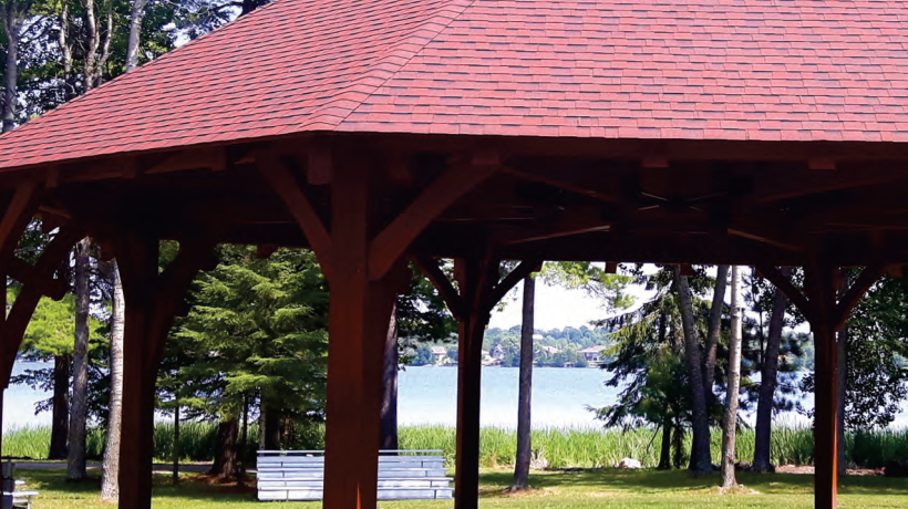 Powwow grounds with the center arbor centered in the picture. There is a lake in the background.
